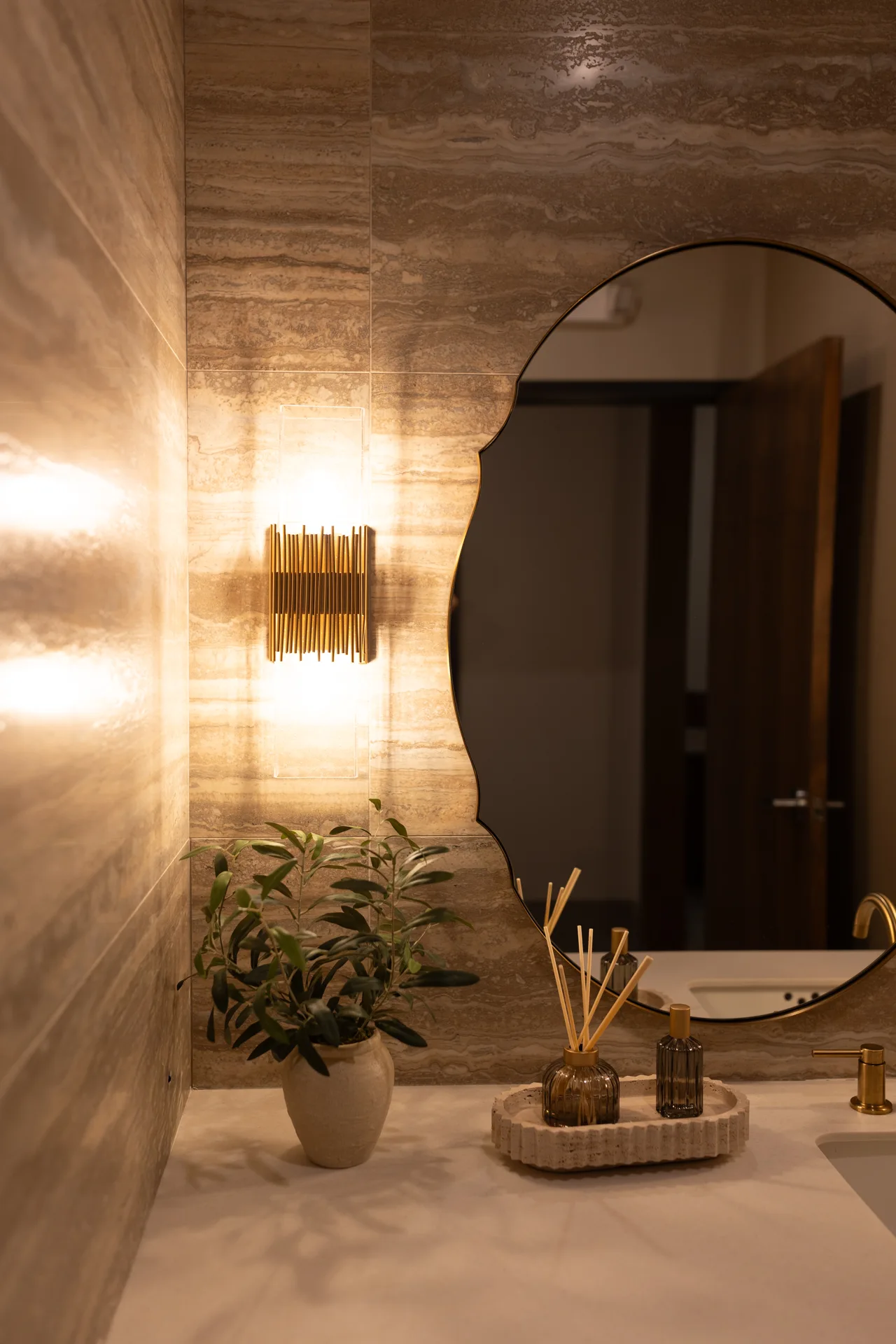 An arched mirror, warm wall lighting and stone finishes inside the office